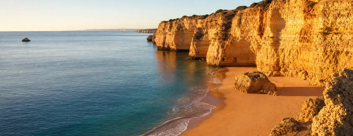 Kustlijn van de Algarve met kliffen en een leeg strand in de late middagzon