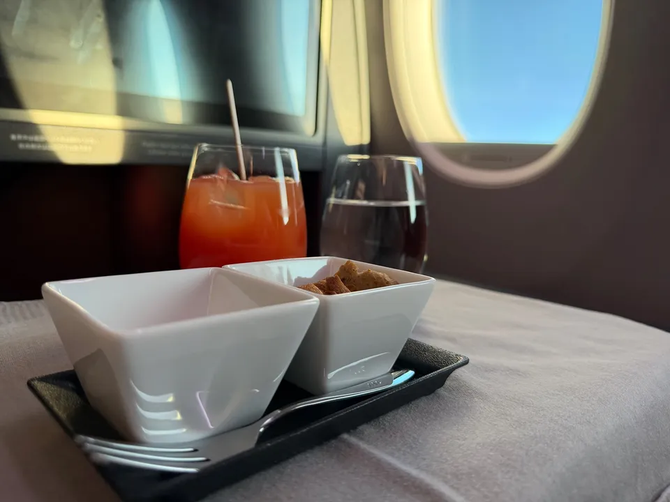 Amuse en een cocktail op een gedekt tafeltje naast het vliegtuigraam