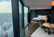 Hotelkamer met kingsize bed en een raamwand die uitkijkt over de daken van Tokyo