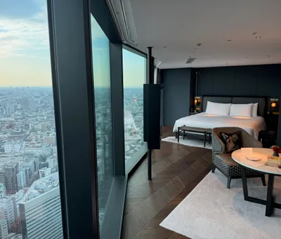 Hotelkamer met kingsize bed en een raamwand die uitkijkt over de daken van Tokyo