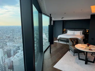 Hotelkamer met kingsize bed en een raamwand die uitkijkt over de daken van Tokyo