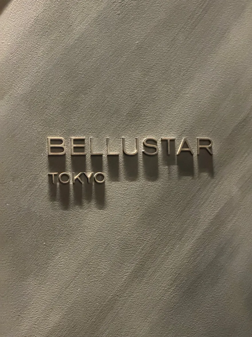 De naam Bellustar Tokyo in reliefletters op een geborsteld metalen wand