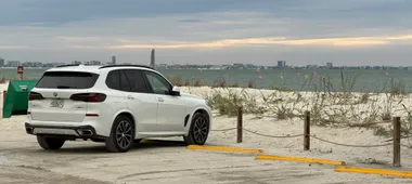 Witte BMW X5 bij het strand van Sanibel onder een bewolkte lucht