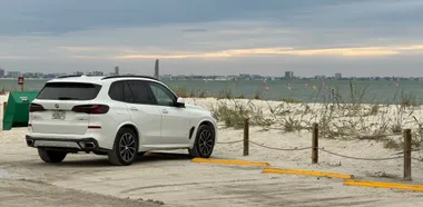 Witte BMW X5 bij het strand van Sanibel onder een bewolkte lucht