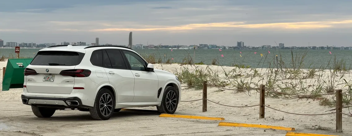Witte BMW X5 bij het strand van Sanibel onder een bewolkte lucht