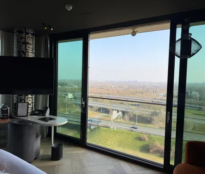 Hoge hotelkamer van Van der Valk Eindhoven-Best met bed, tafel en panoramisch raam