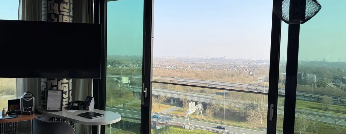 Hoge hotelkamer van Van der Valk Eindhoven-Best met bed, tafel en panoramisch raam
