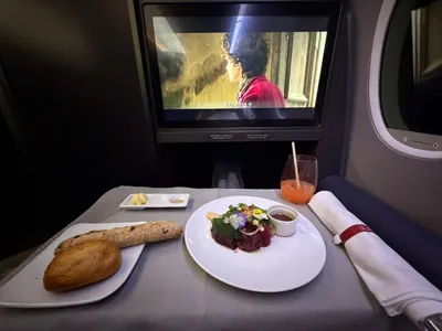 Tafeltje in businessclass met voorgerecht, stokbrood en een scherm, onderweg naar Tokyo