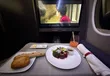 Tafeltje in businessclass met voorgerecht, stokbrood en een scherm, onderweg naar Tokyo