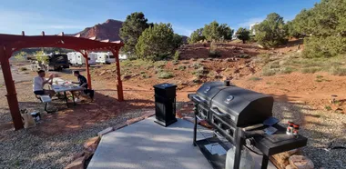 Drie vrienden ontbijten buiten naast hun camper op een kampeerplek in Utah