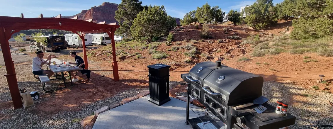 Drie vrienden ontbijten buiten naast hun camper op een kampeerplek in Utah