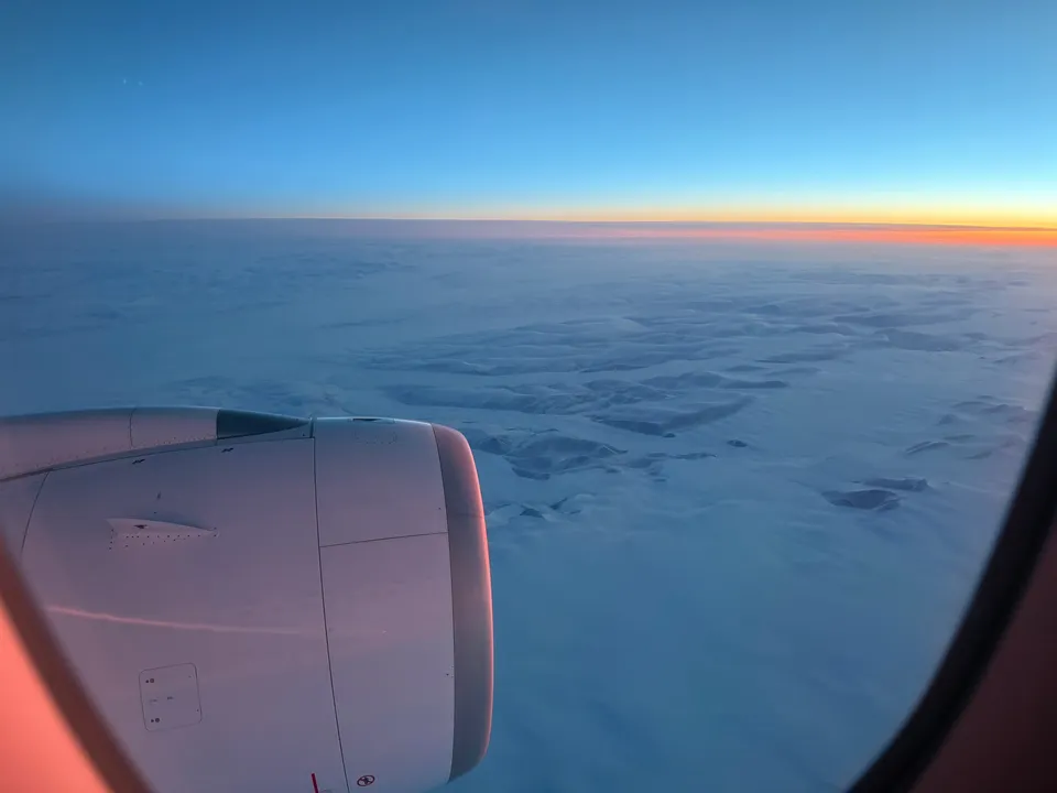 Vliegtuigmotor boven een gesloten wolkendek met de zon laag aan de horizon