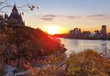 De parlementsgebouwen van Ottawa bij zonsondergang boven de rivier
