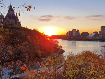 De parlementsgebouwen van Ottawa bij zonsondergang boven de rivier