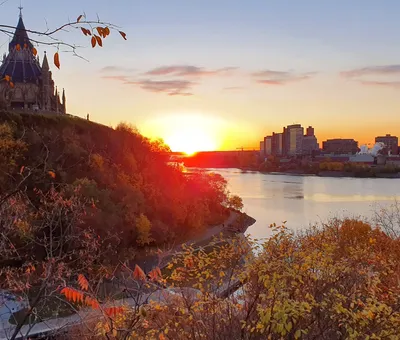 De parlementsgebouwen van Ottawa bij zonsondergang boven de rivier