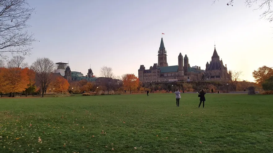 De parlementsgebouwen van Ottawa gezien vanaf een grasveld in de avondzon