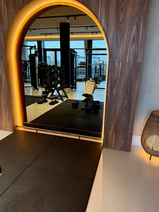 Doorkijk door een verlichte boog naar de sportschool van het hotel in Best