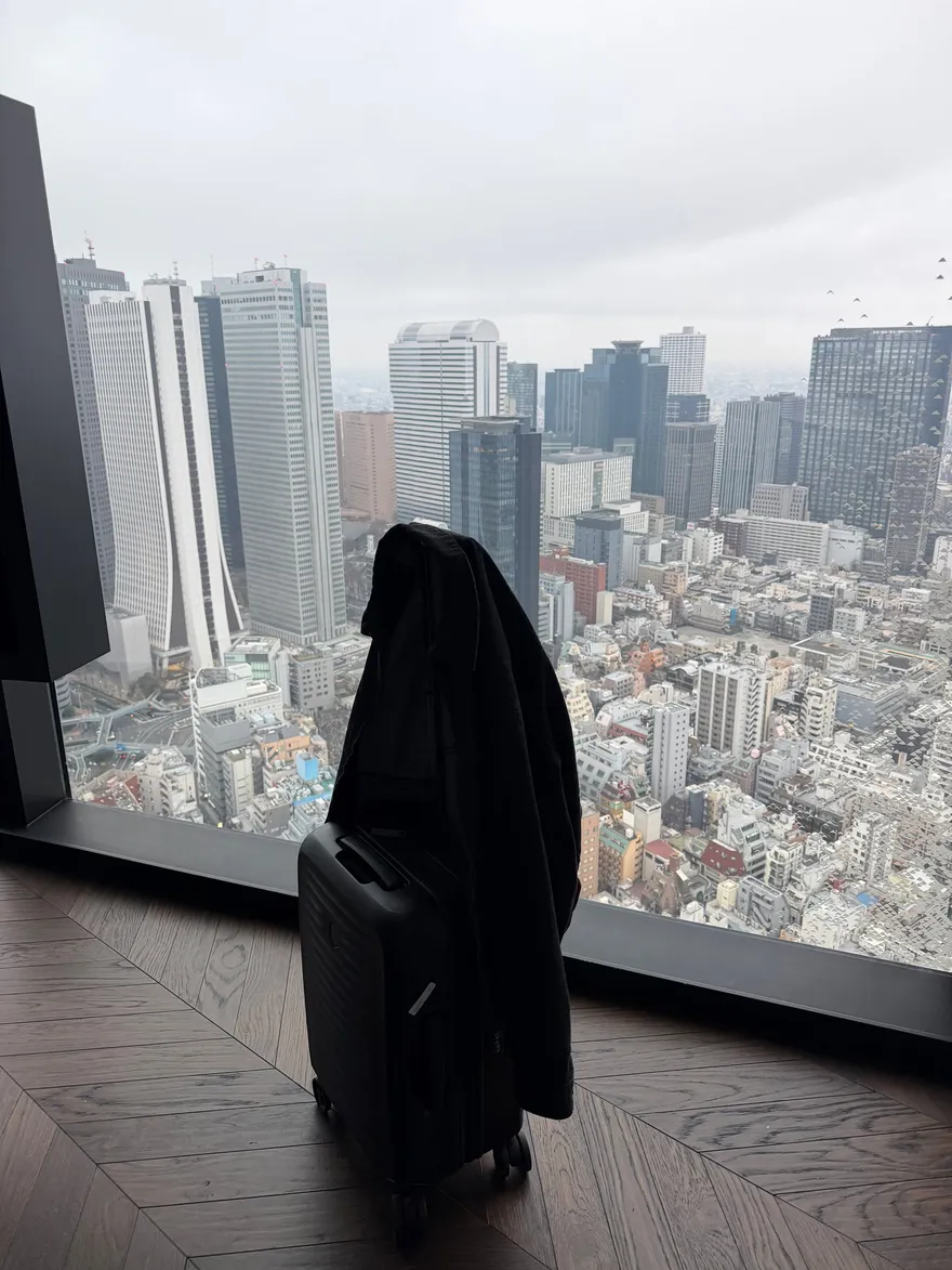 Silhouet van een jas bij een raamwand van vloer tot plafond met de skyline van Tokyo in de ochtend
