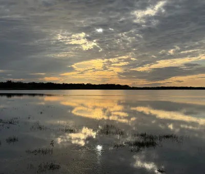 Zonlicht door wolken boven stil water bij Myakka in december