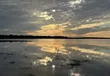Zonlicht door wolken boven stil water bij Myakka in december