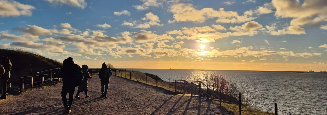 Zonsondergang over de Finse Golf vanaf het vestingeiland Suomenlinna, met wandelaars op het pad